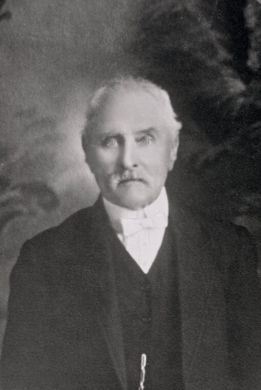 Studio portrait of an elderly man with white hair and a moustache